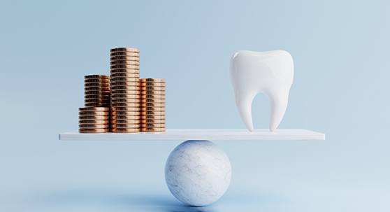 Coins and a model tooth placed on a balance board 