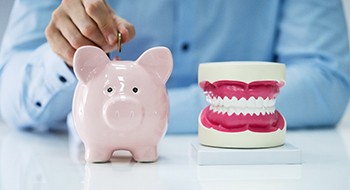 A pink piggy bank set next to a model jaw