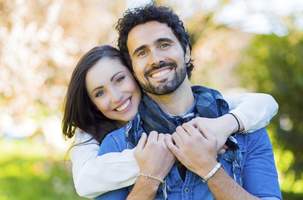Man and woman with aligned smiles after Invisalign orthodontic treatment