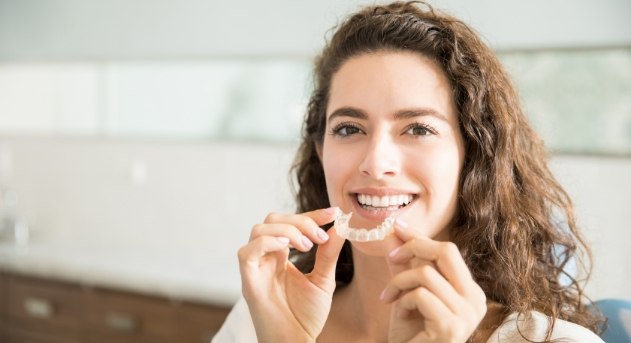 Smiling woman holding her Invisalign tray