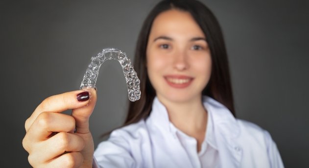 Woman holding up an Invisalign clear aligner