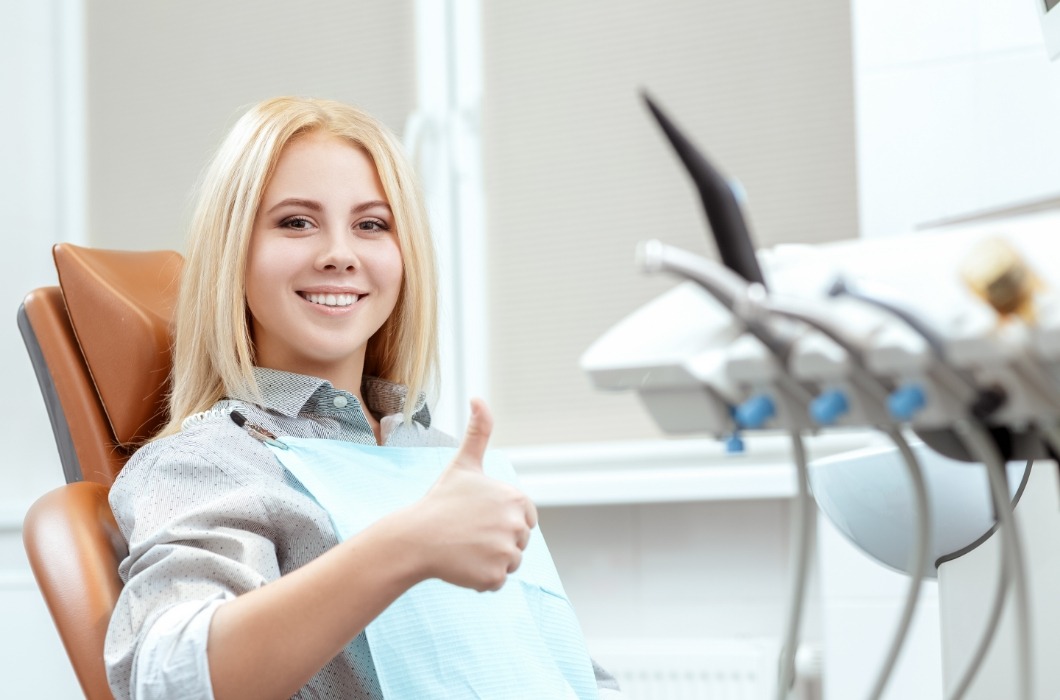 Woman smiling and giving thumbs up find dental chair