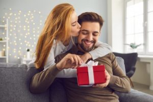 a woman giving her boyfriend the gift of teeth whitening